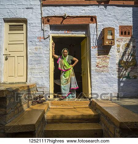 Stock Photograph - An Indian woman stands in the doorway of her home; Jaisalmer, Rajasthan, India. Fotosearch