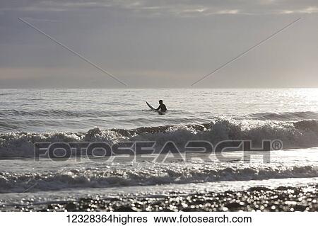 Back Lit Surfer Sitting On Surfboard In Kachemak Bay, Homer, Southcentral Alaska, USA View Large Photo Image Stock Photograph - Back Lit Surfer Sitting On Surfboard In Kachemak Bay, Homer, Southcentral Alaska, USA. Fotosearch