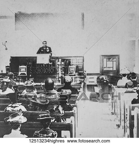 Stock Photograph - Black and white historic image of a preacher in a pulpit and the congregation in the wooden pews. Fotosearch