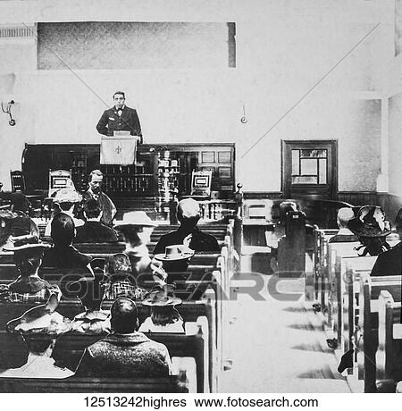 Stock Photograph - Black and white historic image of a preacher in a pulpit and the congregation in the wooden pews. Fotosearch