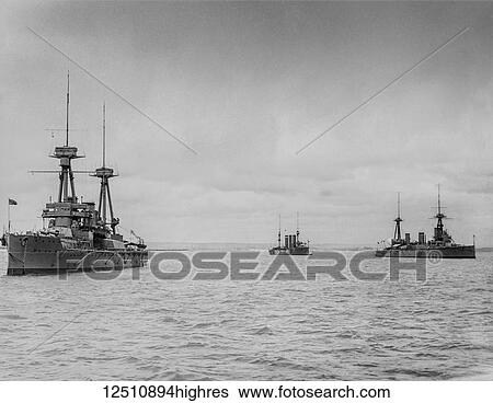 Stock Photograph - Black and white image of ships moored in the ocean under a cloudy sky. Fotosearch