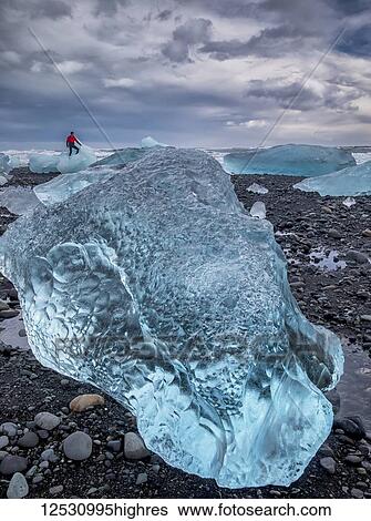 Blue ice on the shore of Jokulsarlon with a man standing on an iceberg in the distance, South coast; Iceland View Large Photo Image Stock Photograph - Blue ice on the shore of Jokulsarlon with a man standing on an iceberg in the distance, South coast; Iceland. Fotosearch