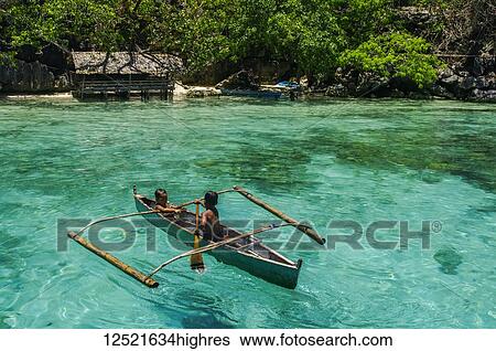 Boys paddling in an outrigger canoe, fishing in the turquoise waters of the Indian Ocean; Andaman Islands, India View Large Photo Image Stock Photograph - Boys paddling in an outrigger canoe, fishing in the turquoise waters of the Indian Ocean; Andaman Islands, India. Fotosearch