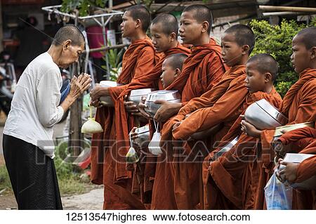 Stock Photograph - Buddhist monks receiving alms on a street; Battambang, Cambodia. Fotosearch