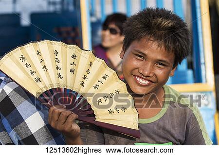 Stock Photograph - Cambodian boy holding a fan, Tonle Sap; Siem Reap, Cambodia. Fotosearch