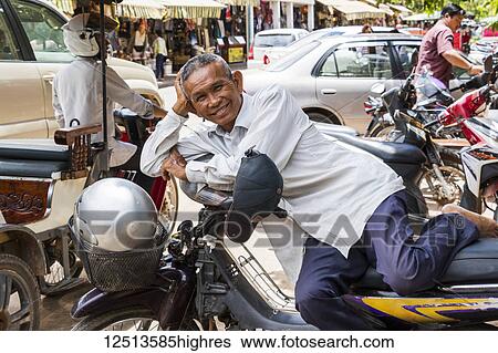 Cambodian man resting on a motorcycle; Siem Reap, Cambodia View Large Photo Image Stock Photograph - Cambodian man resting on a motorcycle; Siem Reap, Cambodia. Fotosearch