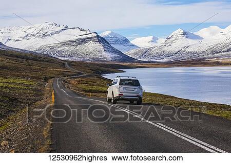 Stock Photograph - Car driving along a coastal road in the East Fjords of Iceland; East Fjords, Iceland. Fotosearch