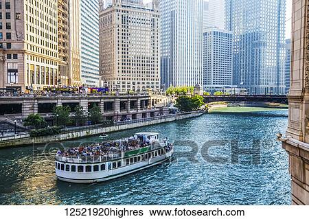 Stock Photograph - Chicago architecture lining the river with a tour boat; Chicago, Illi0is, United States of America. Fotosearch