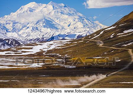 Classic view of Denali looming over a bus traveling along the road in Denali National Park near Stony Pass in early summer; Alaska, United States of America View Large Photo Image Stock Photograph - Classic view of Denali looming over a bus traveling along the road in Denali National Park near Stony Pass in early summer; Alaska, United States of America. Fotosearch