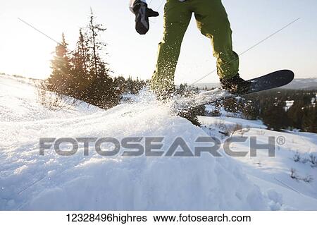 Stock Photograph - Close-up of a snowboarder just lifting off a snow ramp, South-central Alaska; Homer, Alaska, United States of America. Fotosearch