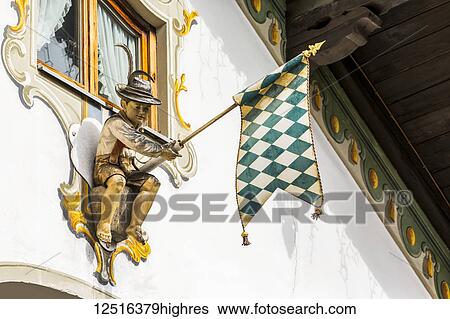 Close-up of decorative sculputure holding a flag on side of a painted window frame on building; Grainau, Bavaria, Germany View Large Photo Image Stock Photograph - Close-up of decorative sculputure holding a flag on side of a painted window frame on building; Grainau, Bavaria, Germany. Fotosearch