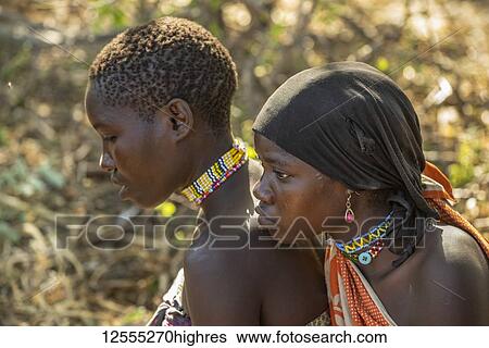 Stock Photograph - Close-up of two young Hadzabe women wearing colourful beaded jewelry near Lake Eyasi; Tanzania. Fotosearch
