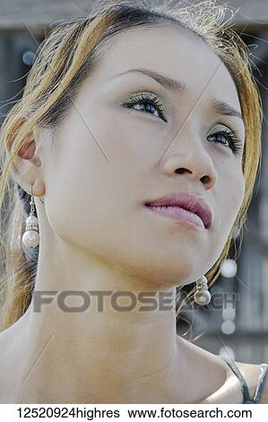 Stock Photograph - Close-up portrait of a beautiful Asian woman wearing cosmetics; Mandalay, Myanmar. Fotosearch