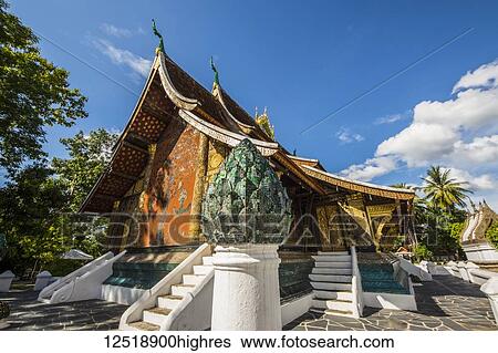 Stock Photograph - Colorful mosaic of the tree of life on a red background, made in the 1960s on the back wall of the sim of Wat Xieng Thong, Luang Prabang, Laos. Fotosearch