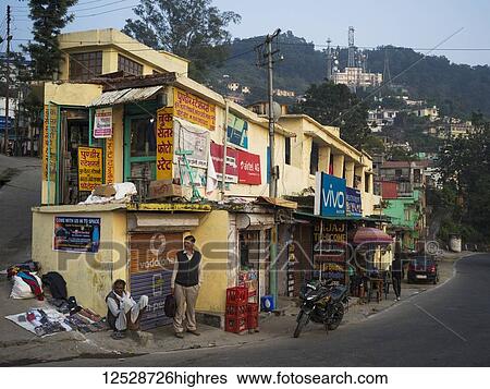 Stock Photograph - Colourful shops and pedestrians in a town in 0rthern India; Narendranager, Uttarakhand, India. Fotosearch