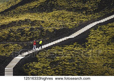 Stock Photograph - Couple going up steps going around the Grabrok crater; Iceland. Fotosearch