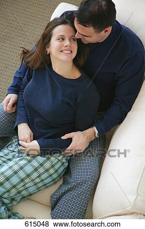 Stock Photo - Couple snuggles on sofa. Fotosearch