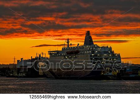 Stock Photograph - Cruise ship docked along a waterfront on the River Tyne under a brilliant sunset sky; South Shields, Tyne and Wear, England. Fotosearch