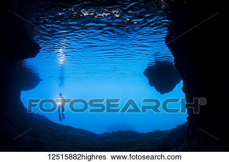 Stock Photograph - Diver at the entrance to a cavern off the island of Gato, Bohol Sea, Philippines. Fotosearch