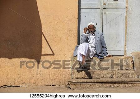 Stock Photograph - Eritrean man sitting on steps outside a door; Asmara, Central Region, Eritrea. Fotosearch