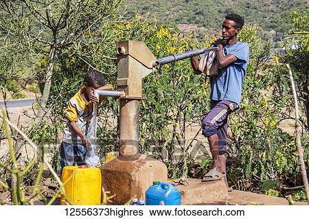 Stock Photograph - Ethiopian man pumping water; Addis Zemen, Amhara Region, Ethiopia. Fotosearch