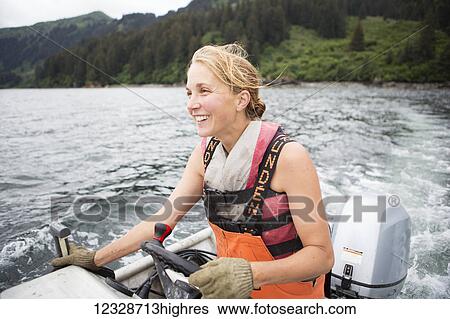 Stock Photograph - Female set-netter driving her set-net skiff near Seldovia, South-central Alaska; Alaska, United States of America. Fotosearch