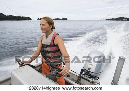 Stock Photograph - Female set-netter driving her set-net skiff near Seldovia, South-central Alaska; Alaska, United States of America. Fotosearch