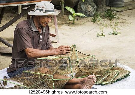 Fisherman sitting and repairing a net; Hoi An Ancient Town, Quang Nam, Vietnam View Large Photo Image Stock Photograph - Fisherman sitting and repairing a net; Hoi An Ancient Town, Quang Nam, Vietnam. Fotosearch