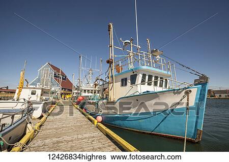 Stock Photograph - Fishing boats docked in a harbour along a wooden dock on the Atlantic coast; Newfoundland, Canada. Fotosearch