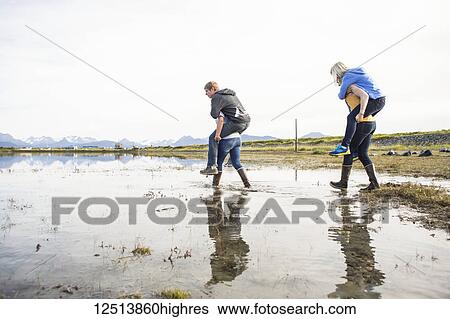 Friends in rubber boots carrying friends across a wet coastal area, South-central Alaska; Homer, Alaska, United States of America View Large Photo Image Stock Photograph - Friends in rubber boots carrying friends across a wet coastal area, South-central Alaska; Homer, Alaska, United States of America. Fotosearch