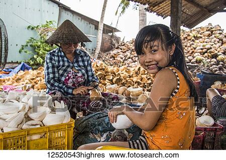 Stock Photograph - Girl and woman at a coconut processing family owned business in the Mekong Delta; Ben Tre, Vietnam. Fotosearch