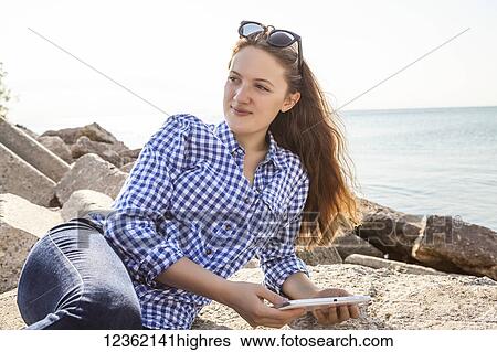 Stock Photograph - Girl using tablet at Woodbine beach in summer; Toronto, Ontario, Canada. Fotosearch