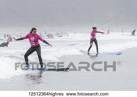 Stock Photograph - Girls learning to surf at Cox Bay Beach, Pacific Rim National Park, Vancouver Island; Tofino, British Columbia, Canada. Fotosearch