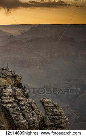 Glowing skies over the horizon at sunset with a tourist standing on a ridge looking out at the Grand Canyon; Grand Canyon Village, Arizona, United States of America View Large Photo Image Stock Photograph - Glowing skies over the horizon at sunset with a tourist standing on a ridge looking out at the Grand Canyon; Grand Canyon Village, Arizona, United States of America. Fotosearch