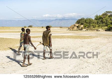 Stock Photograph - Hadzabe hunters returning to camp after a successful morning hunt near Lake Eyasi; Tanzania. Fotosearch