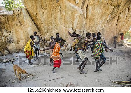 Stock Photograph - Hadzabe men and women dance and sing after a successful morning hunt near Lake Eyasi; Tanzania. Fotosearch