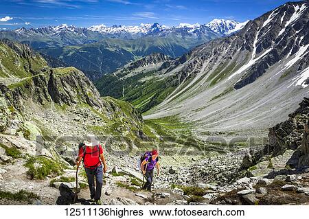 Stock Photograph - Hikers climbing up the 'Fenetre d'Arpette' mountain pass, Swiss Alps mountains in the background; Trient, Martigny, Switzerland. Fotosearch