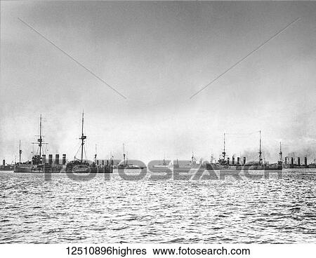 Stock Photograph - Historic black and white image of ships on the ocean under a cloudy sky. Fotosearch