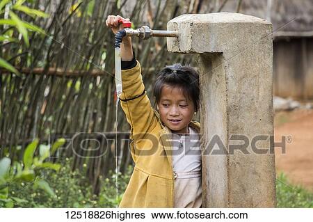 Stock Photograph - Hmong girl playing with a water tap in Na Kam Peng, also called Bomb Village, Xiangkhouang, Laos. Fotosearch