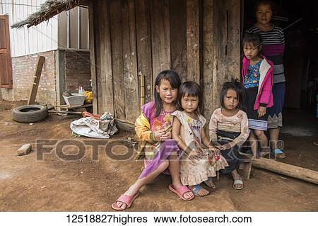 Stock Photograph - Hmong woman and four girls in front of their house in Na Kam Peng, also called Bomb Village; Xiangkhouang, Laos. Fotosearch