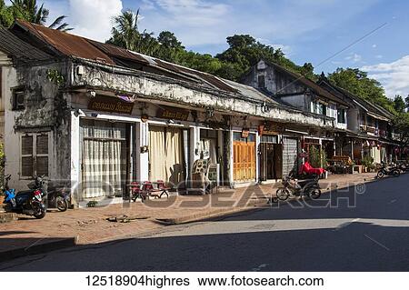 Stock Photograph - Homes and motorcycles parked on Sisavang Vong Road; Luang Prabang, Luang Prabang, Laos. Fotosearch