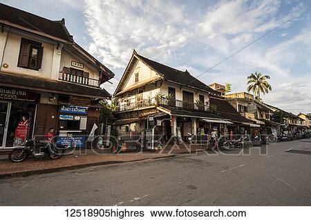 Stock Photograph - Homes, shops and motorcycles parked on Sisavang Vong Road; Luang Prabang, Luang Prabang, Laos. Fotosearch