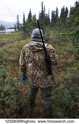 Hunter Stands With His Rife Across His Shoulder Near Lake Iliamna, Southwest Alaska, USA View Large Photo Image Stock Photograph - Hunter Stands With His Rife Across His Shoulder Near Lake Iliamna, Southwest Alaska, USA. Fotosearch