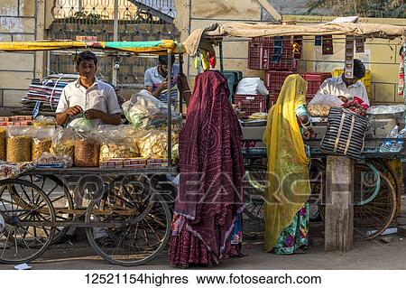 Stock Photograph - Indian women shopping from street vendors; Jaisalmer, Rajasthan, India. Fotosearch