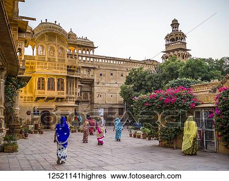 Stock Photograph - Indian women walking in colourful saris in a town square; Jaisalmer, Rajasthan, India. Fotosearch