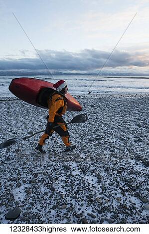 Kayak surfer carrying a paddle and kayak in winter along the snow covered shore, Homer, Southcentral Alaska, USA View Large Photo Image Stock Photograph - Kayak surfer carrying a paddle and kayak in winter along the snow covered shore, Homer, Southcentral Alaska, USA. Fotosearch