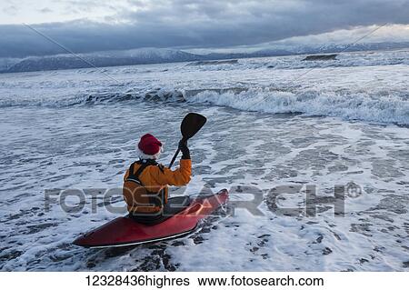 Stock Photograph - Kayak surfer entering the surf in Kachemak Bay, South-central Alaska, Homer, Alaska, United States of America. Fotosearch