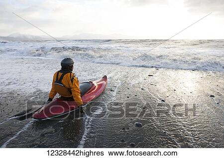 Stock Photograph - Kayak surfer in his boat on the beach, South-central Alaska; Homer, Alaska, United States of America. Fotosearch