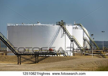 Stock Photograph - Large white metal oil storage tanks with black stairs and blue sky; Cremona, Alberta, Canada. Fotosearch