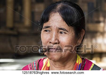 Stock Photograph - Lavae woman smoking a cigar in the ethnic village at Pha Suam, Bolaven Plateau; Champasak, Laos. Fotosearch